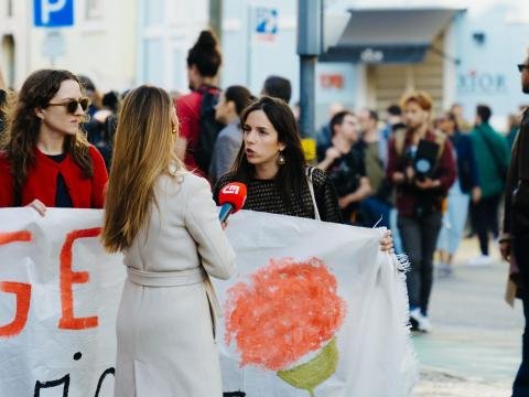 A reporter interviews women holding a banner during a public gathering.