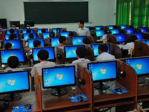 Students work at computers while a teacher guides their classroom learning.
